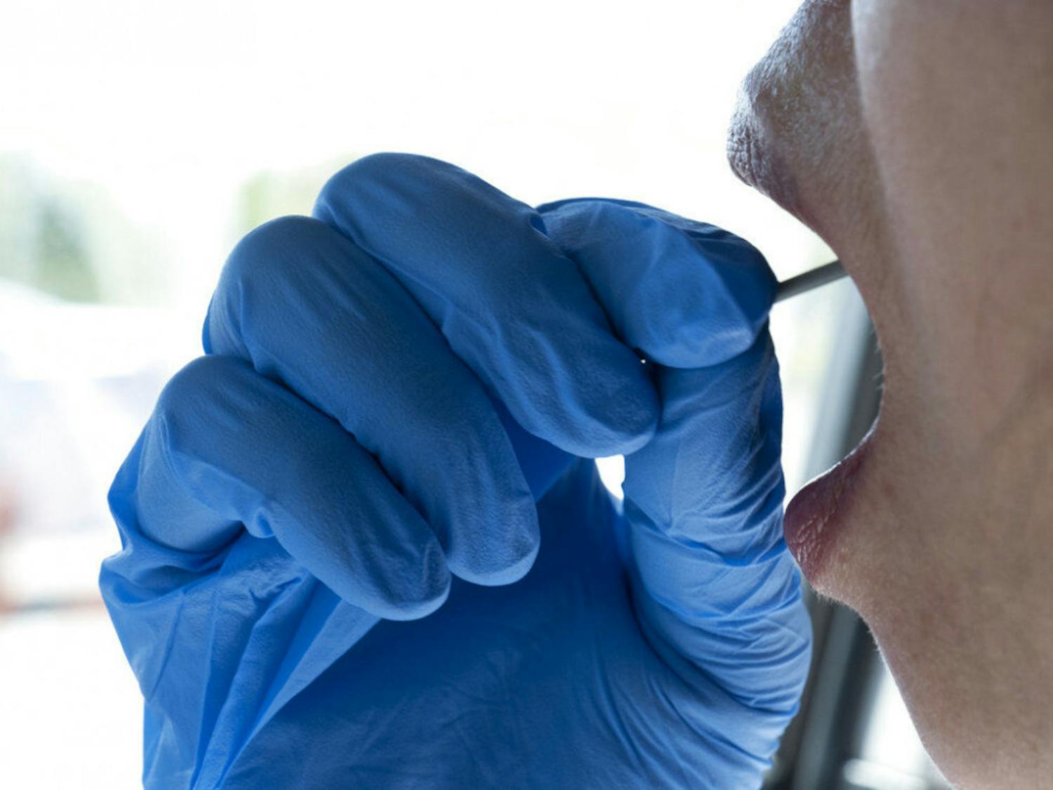 In this Wednesday, May 6, 2020 photo a woman swabs the inside of her mouth during a self administered coronavirus test at a drive through testing site in a parking lot in the Woodland Hills section of Los Angeles. The city of Los Angeles is providing free coronavirus tests to anyone who wants one regardless of whether they have symptoms. The offer reflects a parting with state guidelines after the mayor partnered with a startup testing company. The test the city is offering is easier to administer and doesn't require the scarce supplies that have created bottlenecks for expanded testing across California. (AP Photo/Richard Vogel)