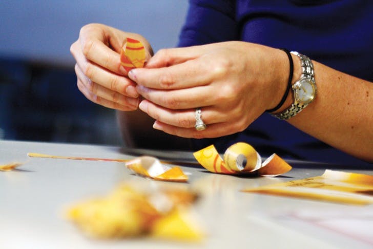 Employees of UF’s Office of Sustainability make Christmas bows out of magazines on Monday at the Reitz Union. The Christmas decorations were created out of sustainable materials.