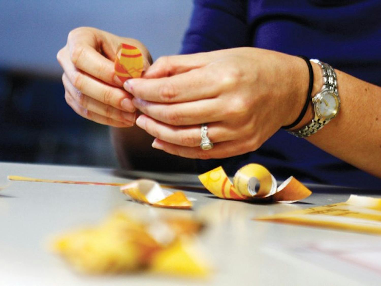 Employees of UF’s Office of Sustainability make Christmas bows out of magazines on Monday at the Reitz Union. The Christmas decorations were created out of sustainable materials.