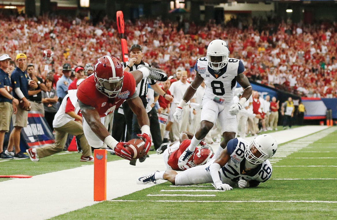 Alabama running back T.J. Yeldon (4) dives into the end zone for a touchdown as West Virginia's Travis Bell (26) and Karl Joseph (8) defend in the first half of an NCAA college football game Saturday, Aug. 30, 2014, in Atlanta.