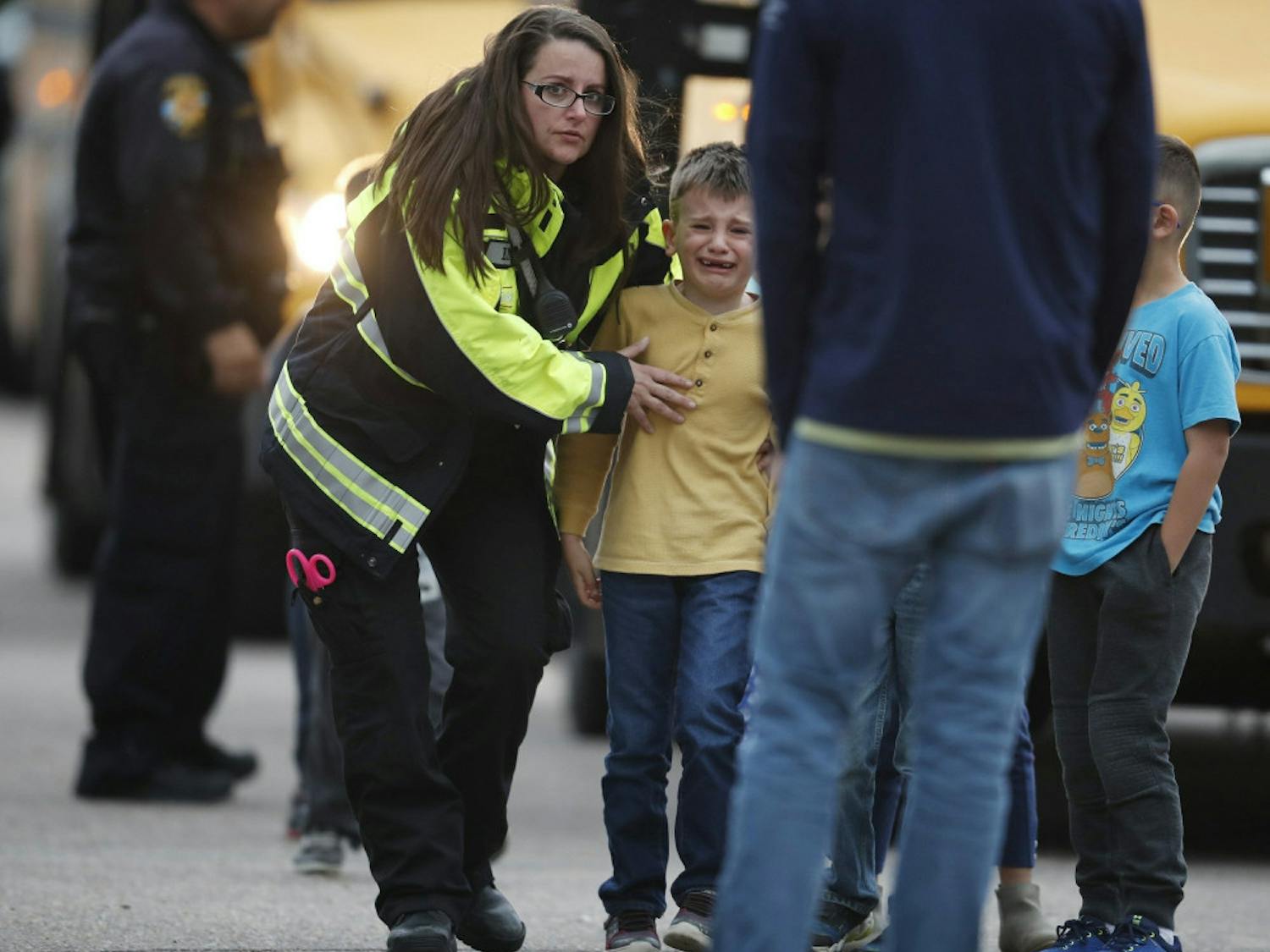 Officials guide students off a bus and into a recreation center where they were reunited with their parents after a shooting at a suburban Denver middle school Tuesday, May 7, 2019, in Highlands Ranch, Colo.