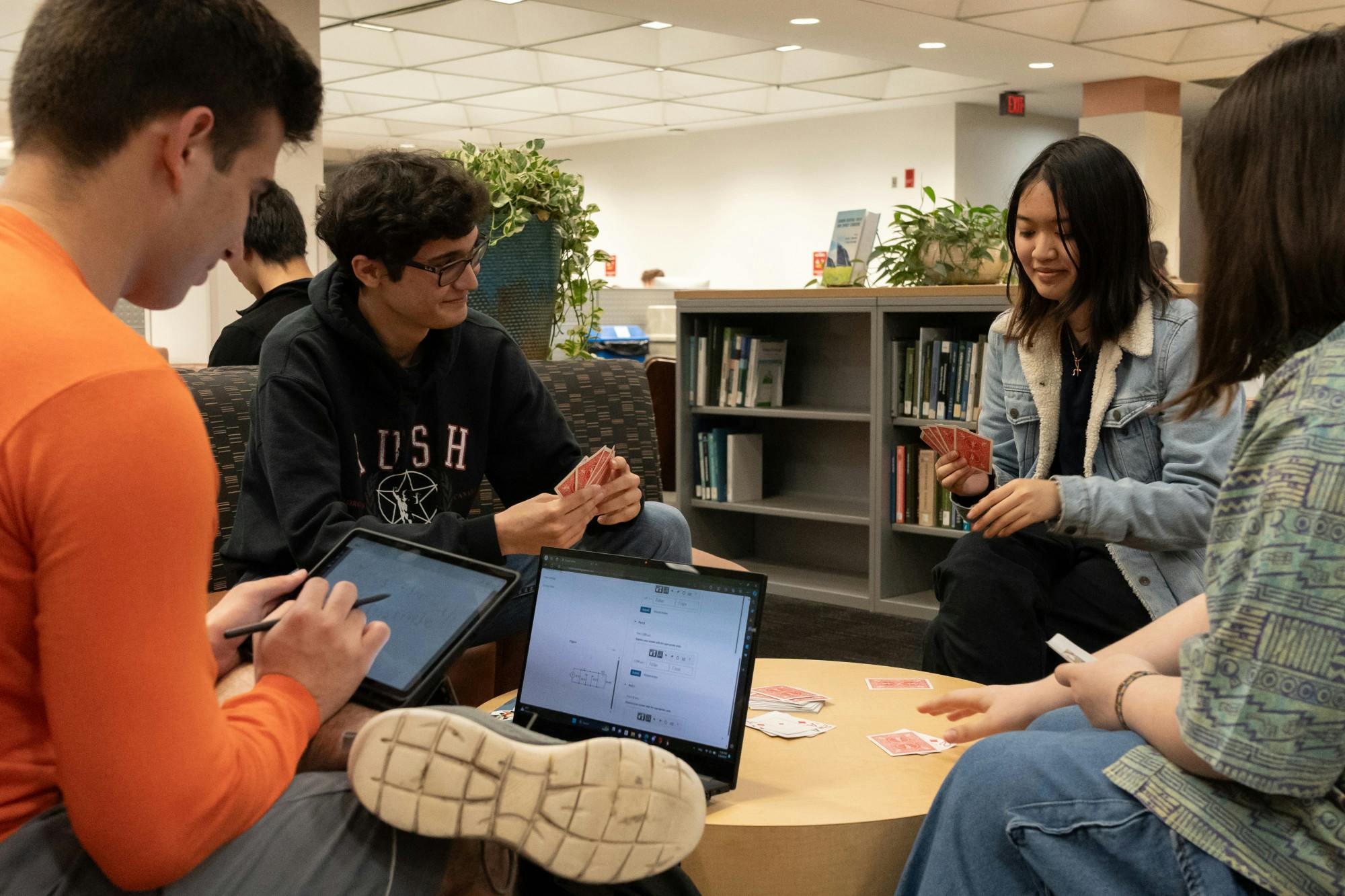Jonathan Pearson, Hailey Pham and Mags Penza play cards while Fernando Guillen studies at Marston Science Library on Sunday, March 3, 2024.
