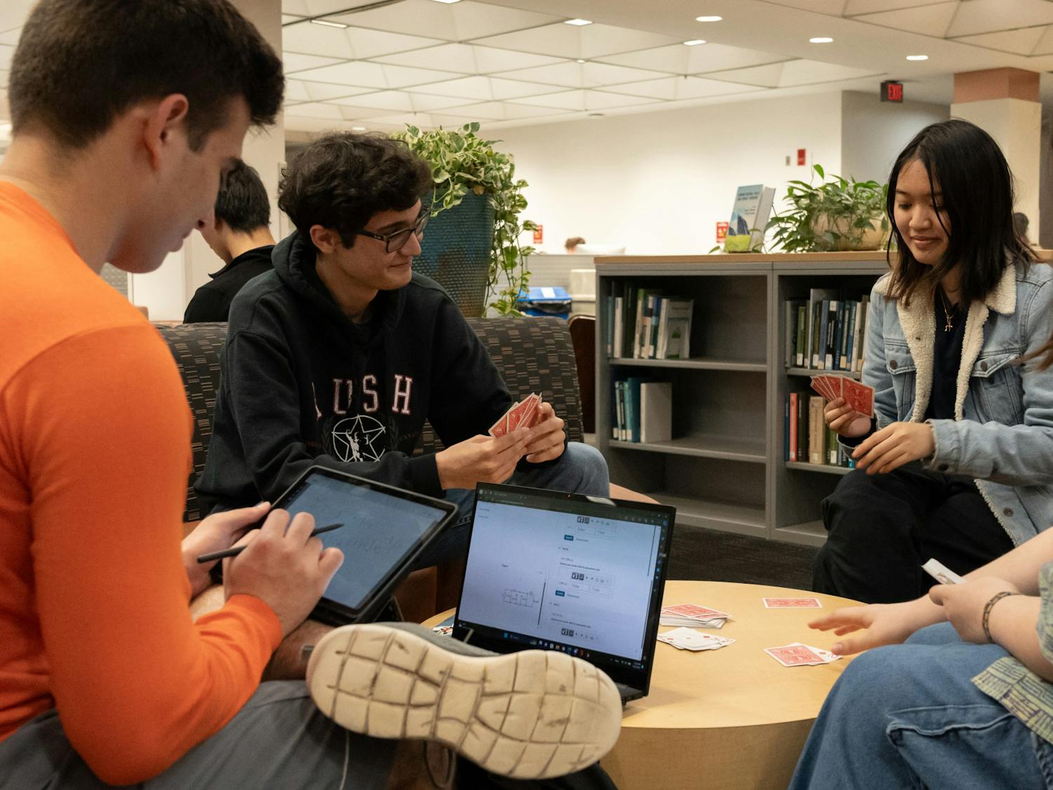 Jonathan Pearson, Hailey Pham and Mags Penza play cards while Fernando Guillen studies at Marston Science Library on Sunday, March 3, 2024.