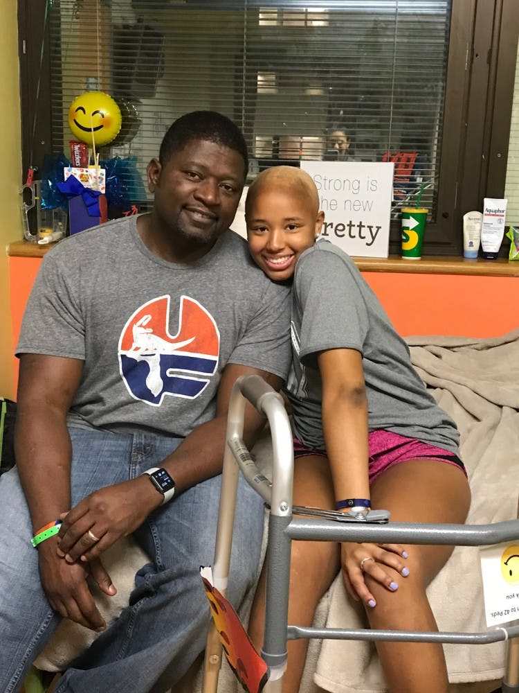Lauren Evans sits with her father, Jerome, at UF Health Shands, where she was receiving cancer treatment. Currently cancer free, Evans attempted to break the selfie world record Sunday after the Florida soccer team's win over LSU in effort to raise awareness for pediatric cancer.   