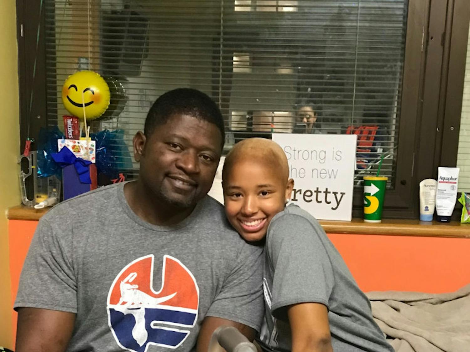 Lauren Evans sits with her father, Jerome, at UF Health Shands, where she was receiving cancer treatment. Currently cancer free, Evans attempted to break the selfie world record Sunday after the Florida soccer team's win over LSU in effort to raise awareness for pediatric cancer.