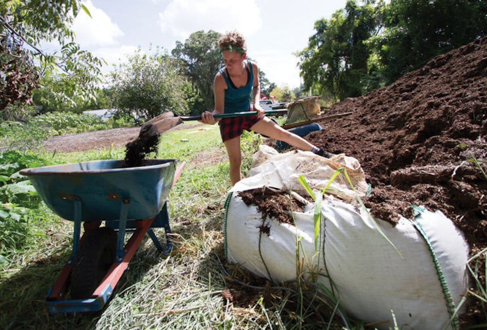 <p>Ellen Vessels, 27, coordinator of the Florida Organic Growers GIFT Gardens program, shovels compost at Porters Community Garden, located at 518 SW Third St.</p>