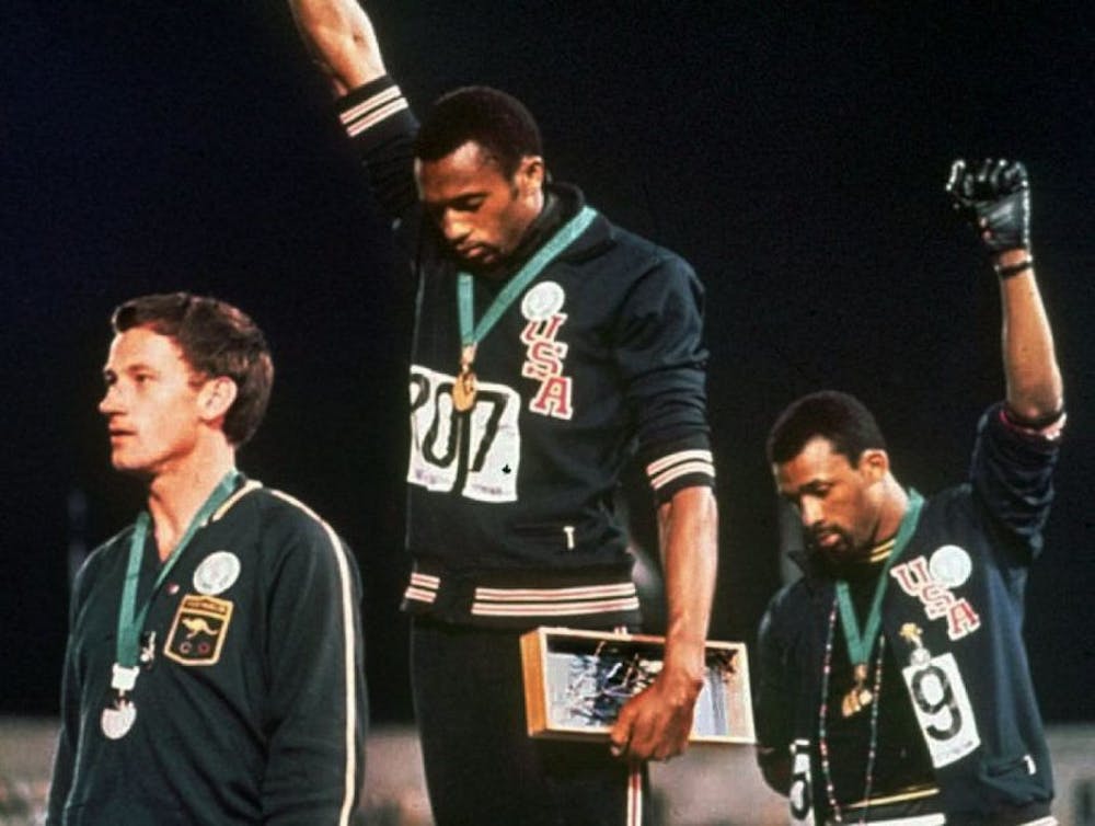 <p>Americans Tommie Smith (center) and John Carlos (right) raised their fists after the 1968 Olympics 200-meter race as "The Star-Spangled Banner" played.&nbsp;</p>