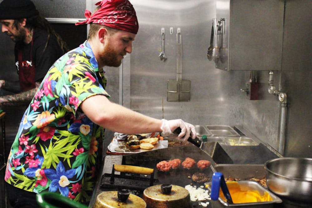 <p>Daniel Gallagher, 25, and Gui Amador, 38, of Go Go Stuff Yourself, prepare food for customers at Gainesville’s first Food Truck Rally on Saturday night.</p>