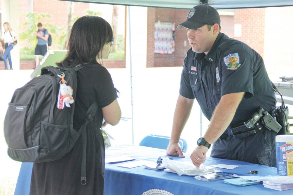University Police Officer Chad Holway, 32, talks with a student about campus safety precautions and different UPD self-defense programs outside of Library West on Tuesday. Holway had a family barbeque to bring in the Labor Day holiday.