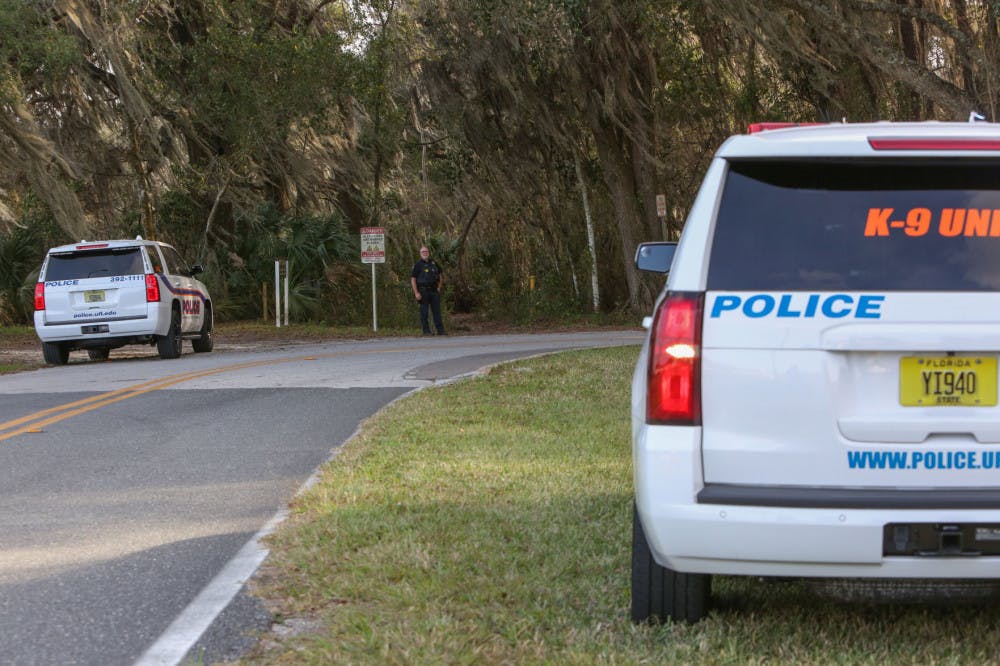 A University of Florida Police Department officer stands in front of a wooded area near the UF College of Veterinary Medicine where officers were searching for a suspect reportedly firing a gun at targets.