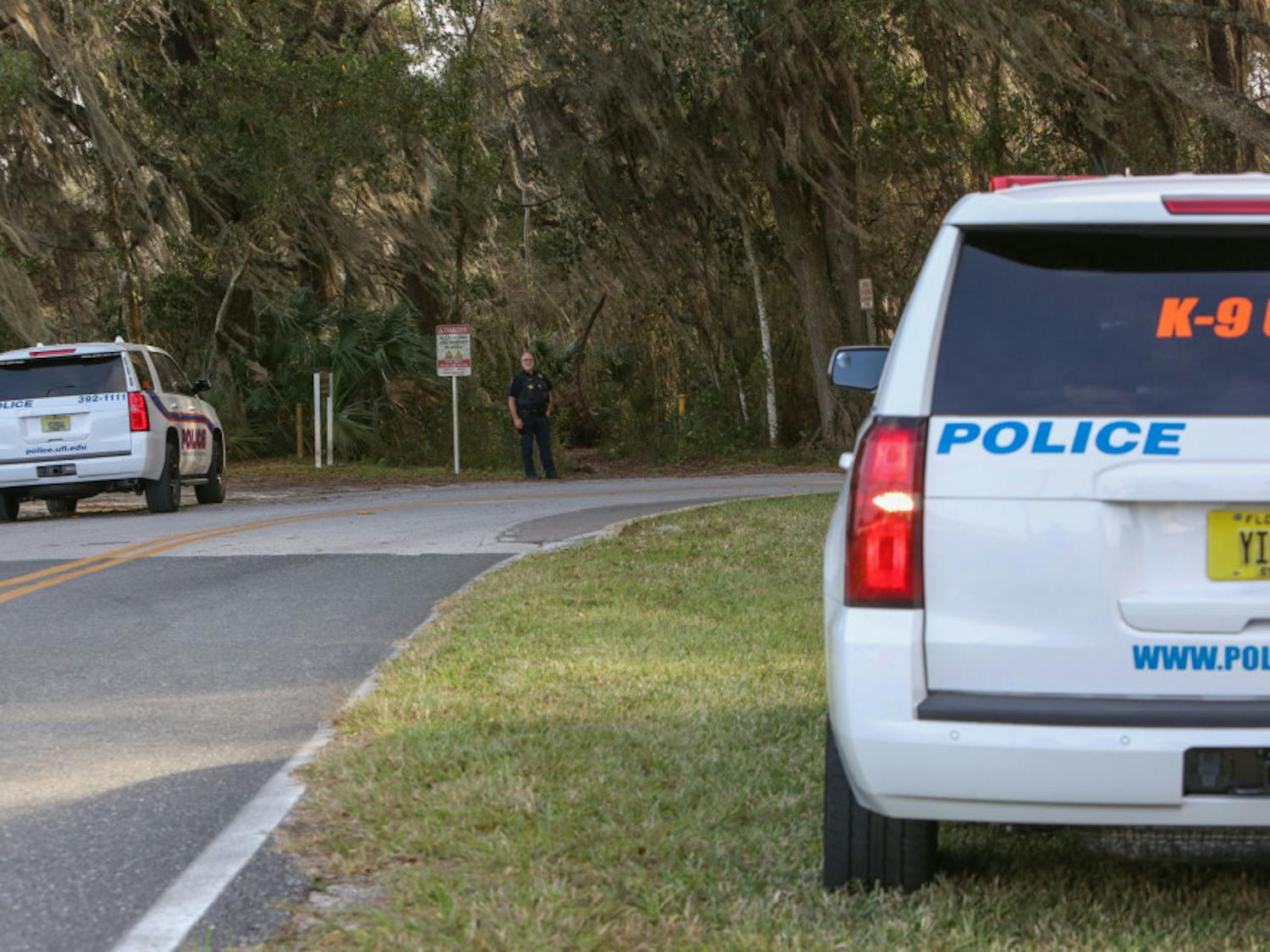 A University of Florida Police Department officer stands in front of a wooded area near the UF College of Veterinary Medicine where officers were searching for a suspect reportedly firing a gun at targets.