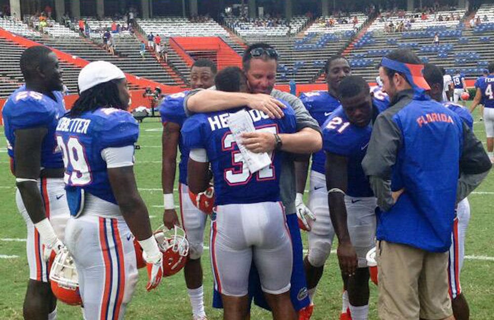 <p>Running backs coach Brian White hugs sophomore running back Mark Herndon during Tuesday's practice at Ben Hill Griffin Stadium. Florida put Herndon and fifth-year safety Tim Clark, both previously walk-ons, on full scholarship Tuesday.</p>