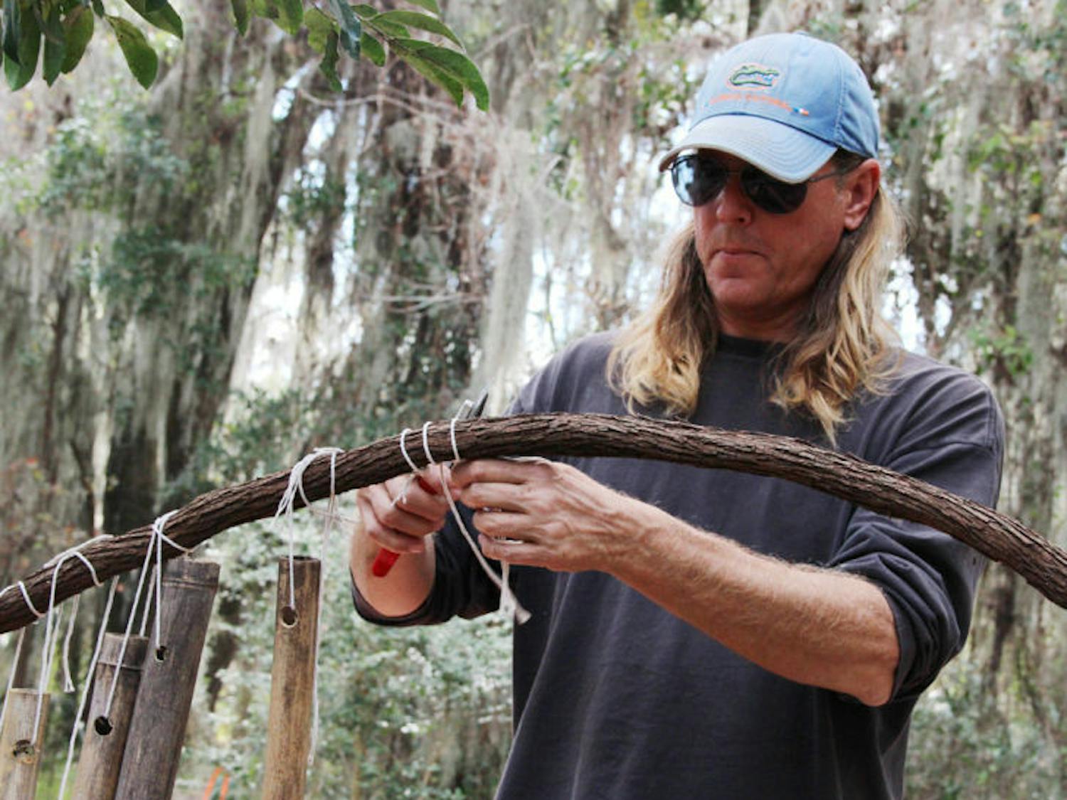 UF greenhouse manager Jeff Hubbard helps dismantle artist Jon Anderson’s “Bambooville” on Tuesday. The university requested Monday that the site be cleared within 72 hours.