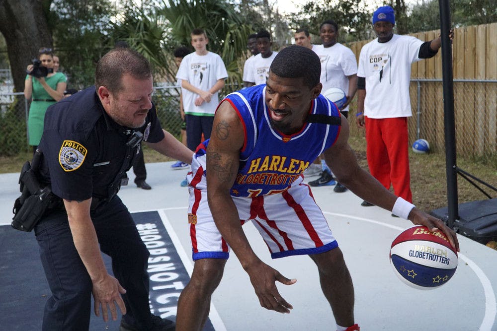 Officer Bobby White plays basketball one-on-one with Anthony “Buckets” Blakes of the Harlem Globetrotters on Tuesday afternoon. Blakes gave 50 free tickets to the neighborhood for Globetrotters game at the O'Connell Center on Thursday.