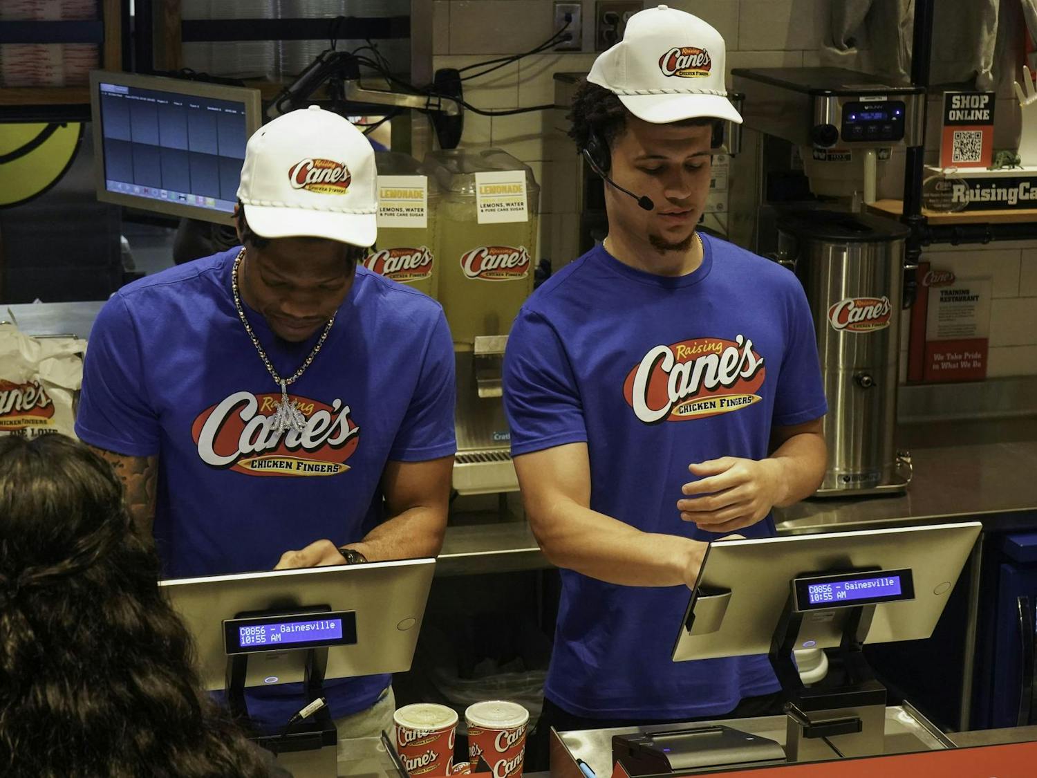 Alijah Martin and Walter Clayton Jr. take orders at Raising Cane's on W University Ave on Thursday, April 10, 2025