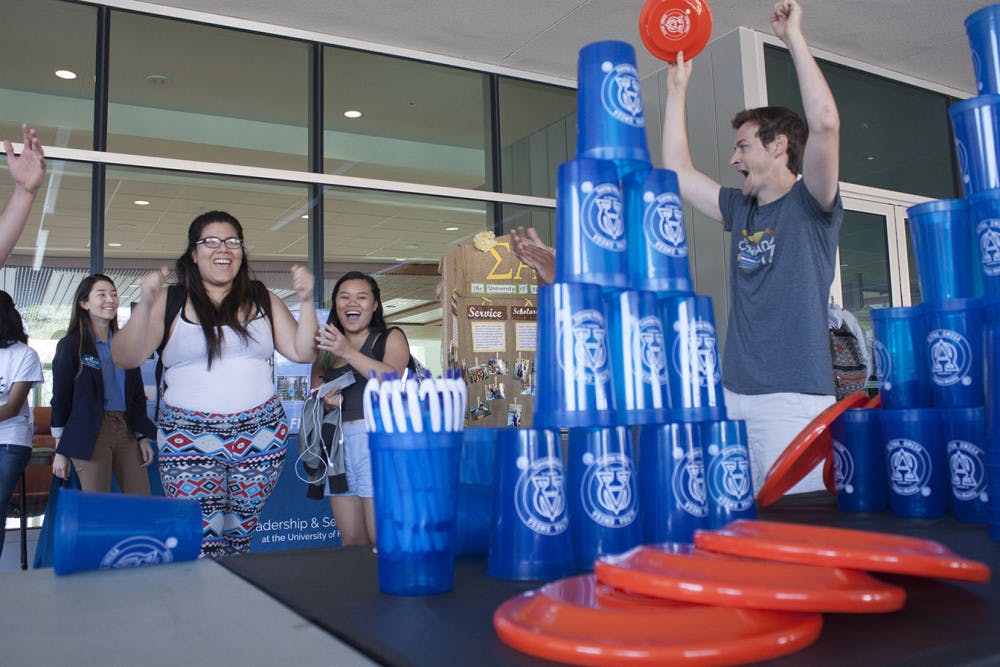 <p>Julisia Hernandez, a 21-year-old mechanical engineering senior, celebrates after winning a flying disc that Kyle Eastman, a 29-year-old alumnus, holds at Alpha Omega Campus Ministry’s booth at the the Spring Student Org Fair on Wednesday. “Anybody can come join,” Eastman said about the ministry.</p>