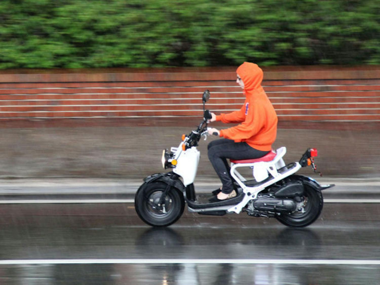 A student rides to UF's campus in the rain Tuesday morning on University Avenue. The early-morning rain could bring cooler temperatures for the upcoming days.