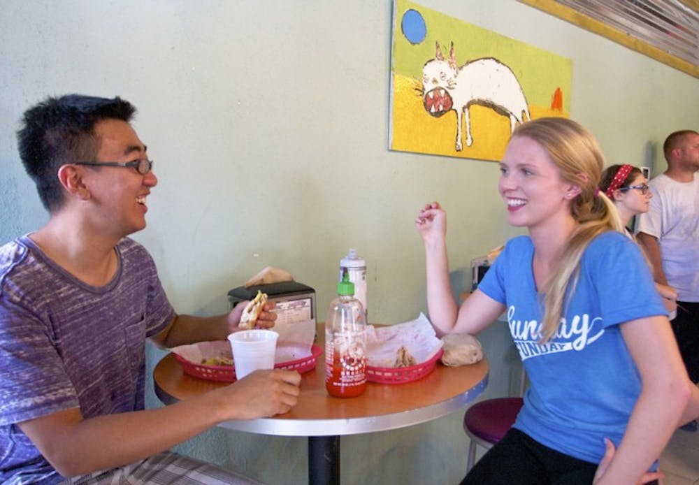<p>Weizhi Cheng, 22, enjoys a Cuban gator sandwich during lunch with Heather Rivers, 22, at the Midtown Flaco’s Cuban Bakery on Wednesday afternoon.</p>