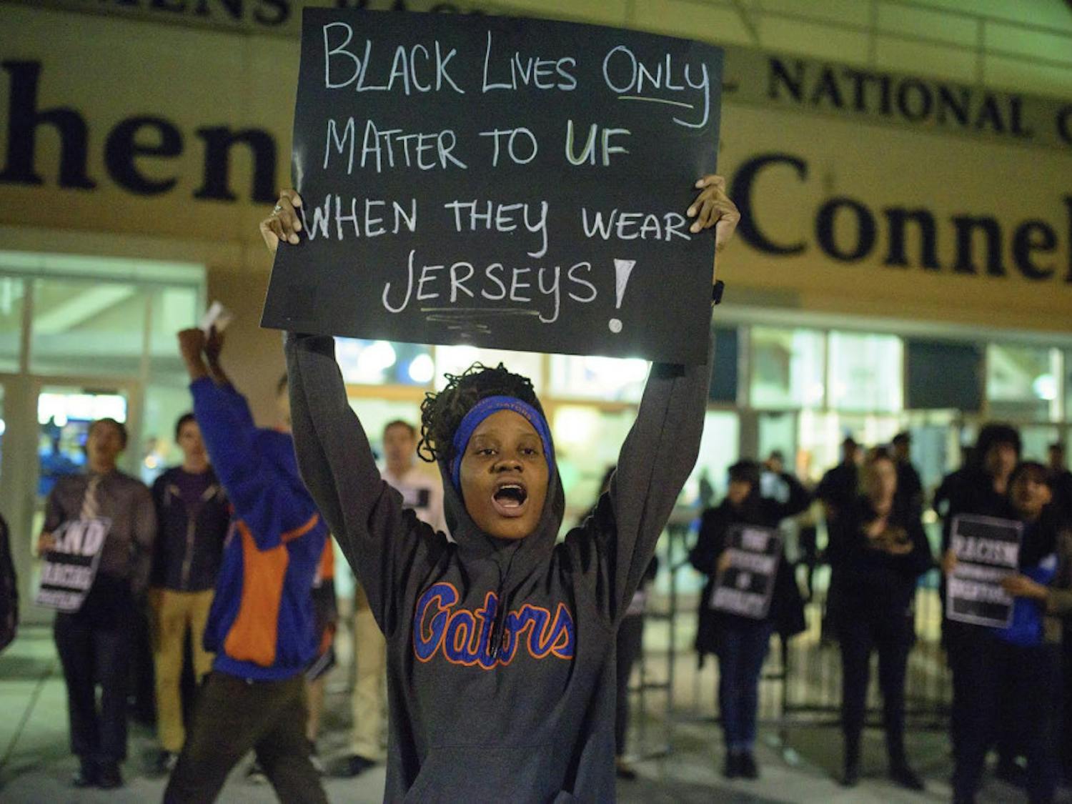 A protester outside the Stephen C. O’Connell center holds a sign with a statement implying the University of Florida is only concerned with African-Americans that participate in athletics at the school.