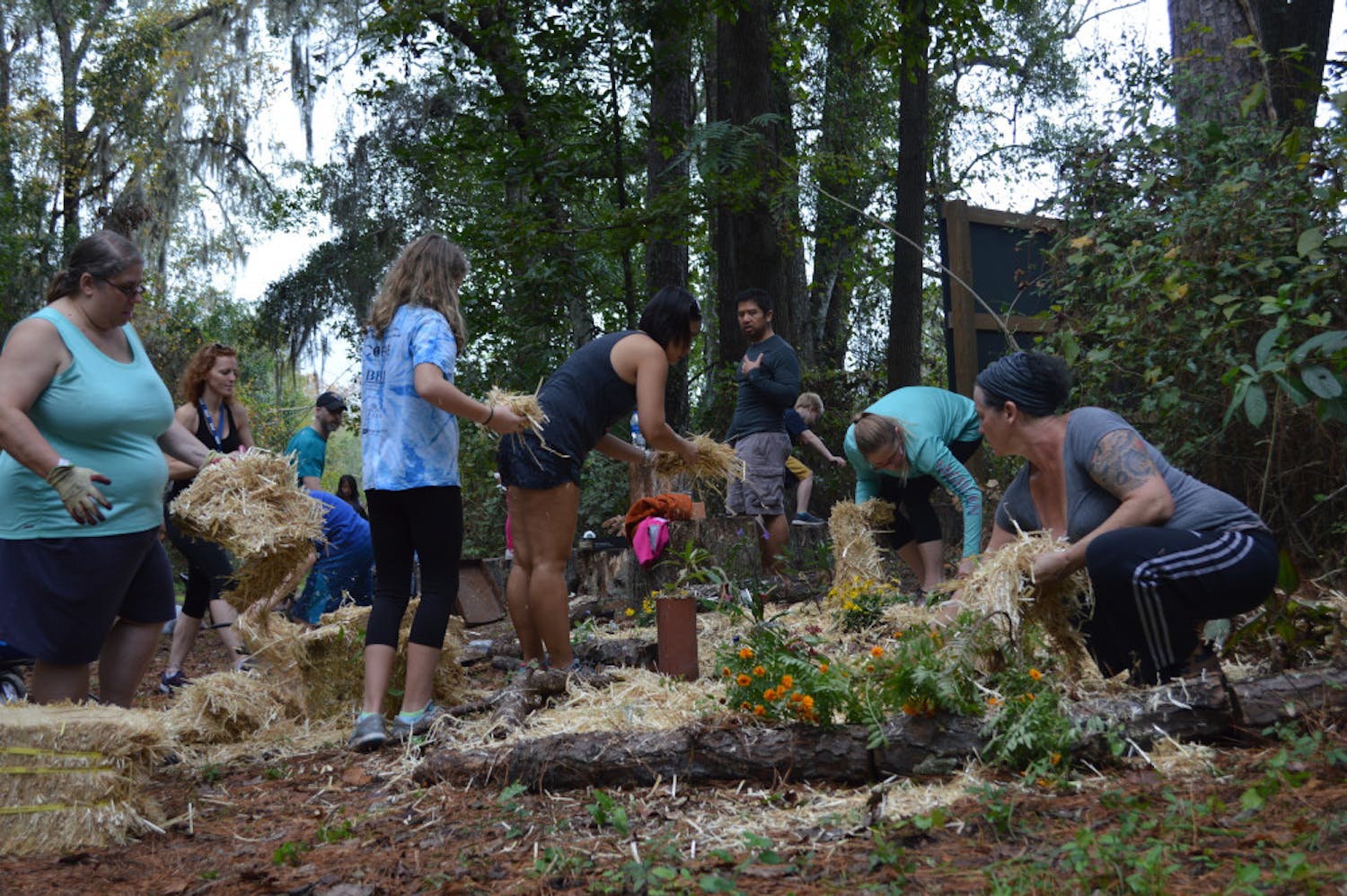 Volunteers spread hay after planting marigolds, milkweed and other perennials beside an outdoor classroom at Stephen Foster Elementary School. They took the day to beautify the campus in the wake of media specialist Leslie Williams’ death. Gillian Sweeney / Alligator Staff 