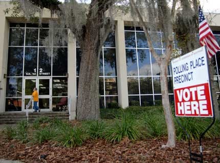 Poll deputy Joseph Antonelli waits to greet early voters in front of the County Administration Building in downtown Gainesville on Thursday.