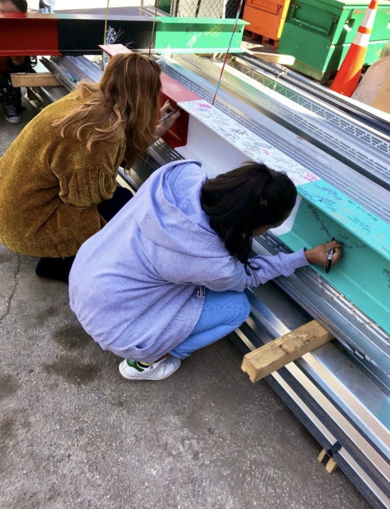 Two students signing the beam at the topping out ceremony on Friday.