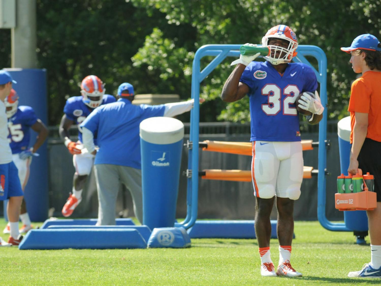 Jordan Cronkrite (32) takes a break from Florida's Spring practice while running backs coach Tim Skipper (middle) watches Mark Thompson (24) run drills. The Gators practiced for two hours at the Sanders Practice Fields on March 30.