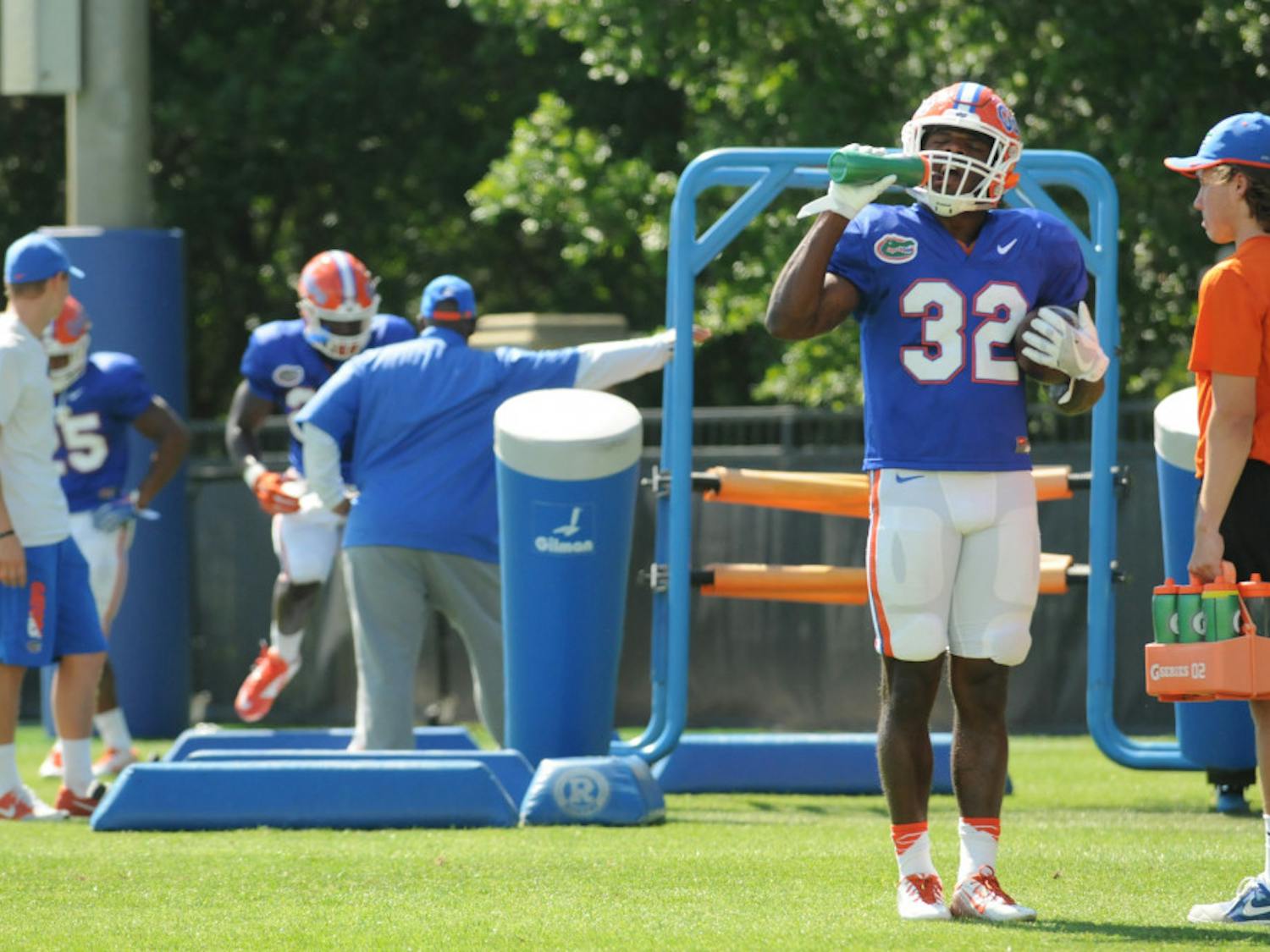 Jordan Cronkrite (32) takes a break from Florida's Spring practice while running backs coach Tim Skipper (middle) watches Mark Thompson (24) run drills. The Gators practiced for two hours at the Sanders Practice Fields on March 30.