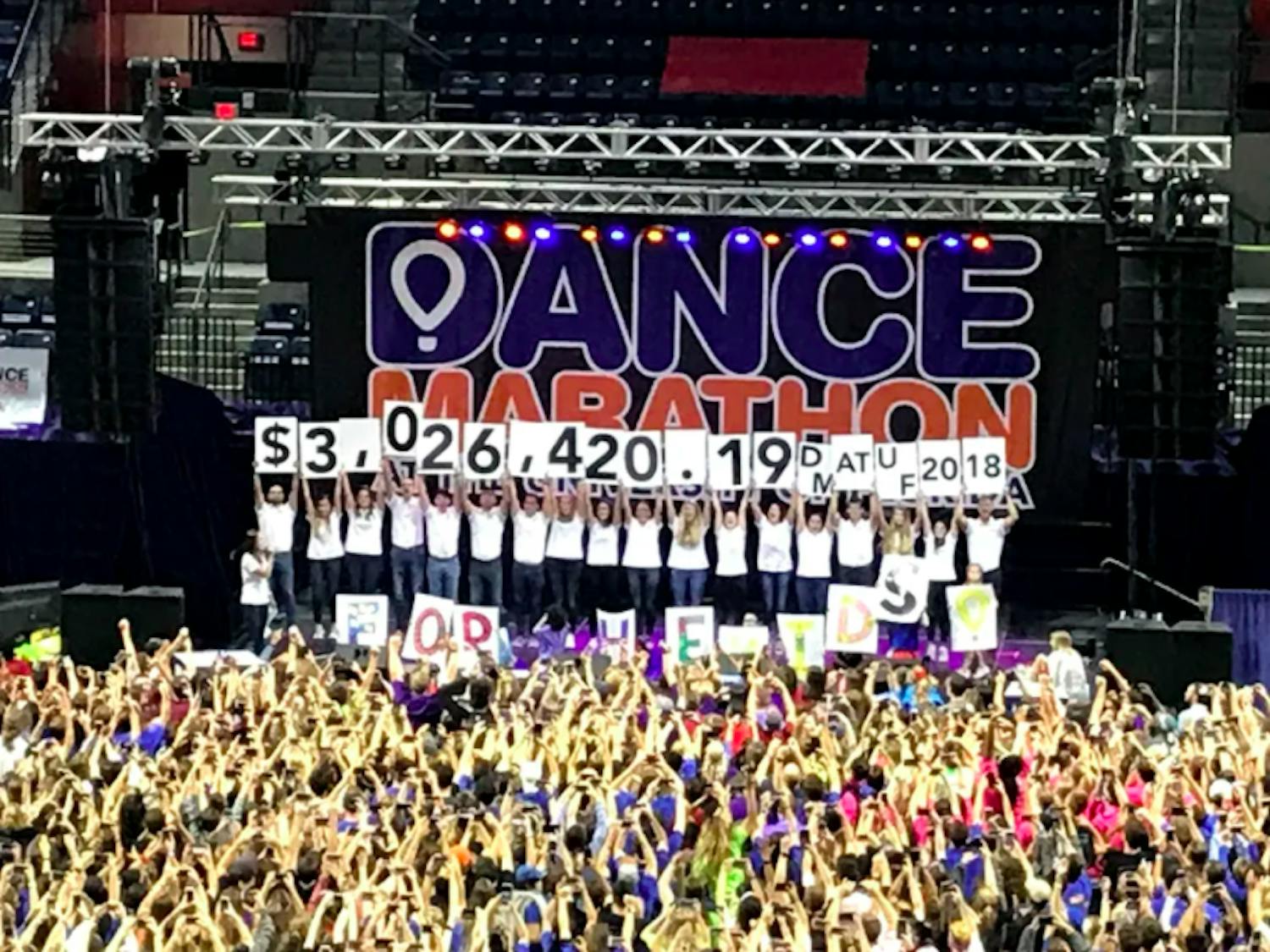 UF Dance Marathon staff members hold signs revealing the total amount of money fundraised this year, totaling $3,026,420.19 for the Children’s Miracle Network.
