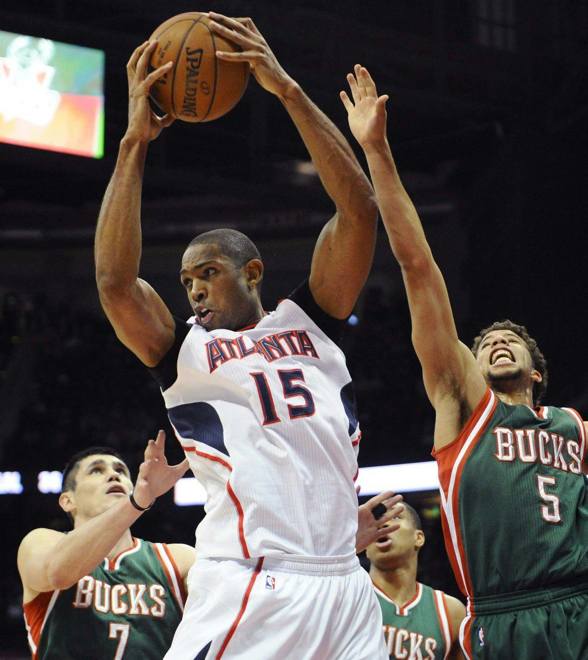 Atlanta Hawks' Al Horford (15) pulls down a rebound over Milwaukee Bucks' Ersan Ilyasova (7) and Michael Carter-Williams (5) in the first half of an NBA basketball game Monday, March 30, 2015, in Atlanta.
