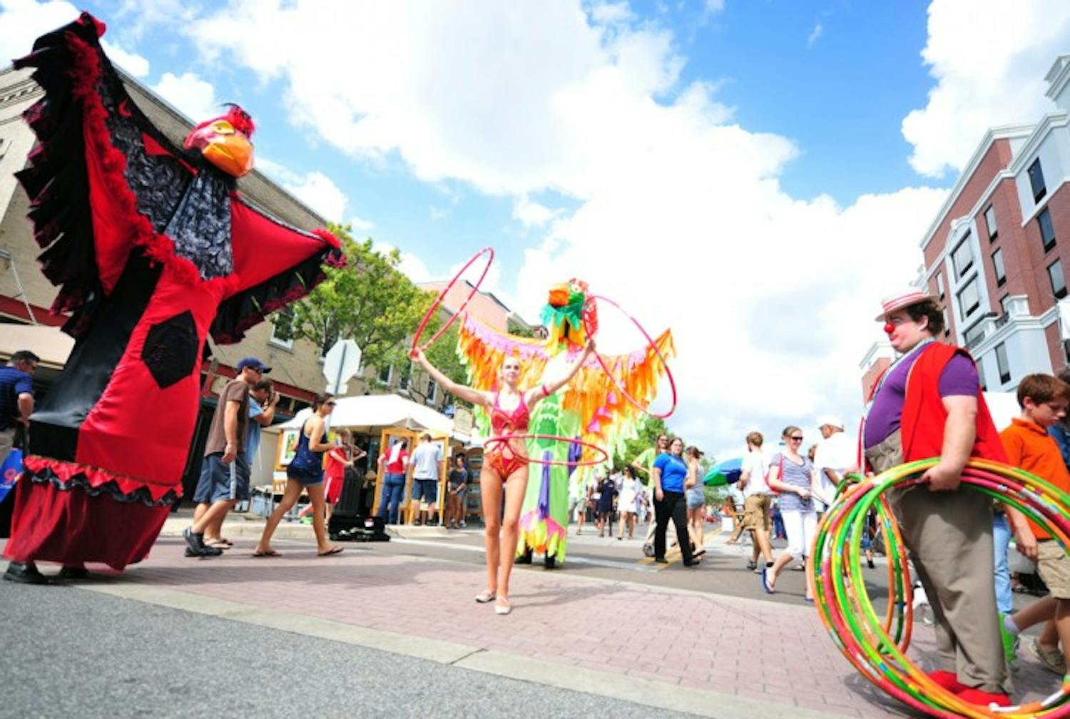 Performers Bethany Chase, in the parrot suit, Elise Duran, 22, and Clay Cox entertain in the streets of downtown Gainesville during the 2012 Downtown Festival and Art Show. They are members of the Rainbow Tiger Circus.