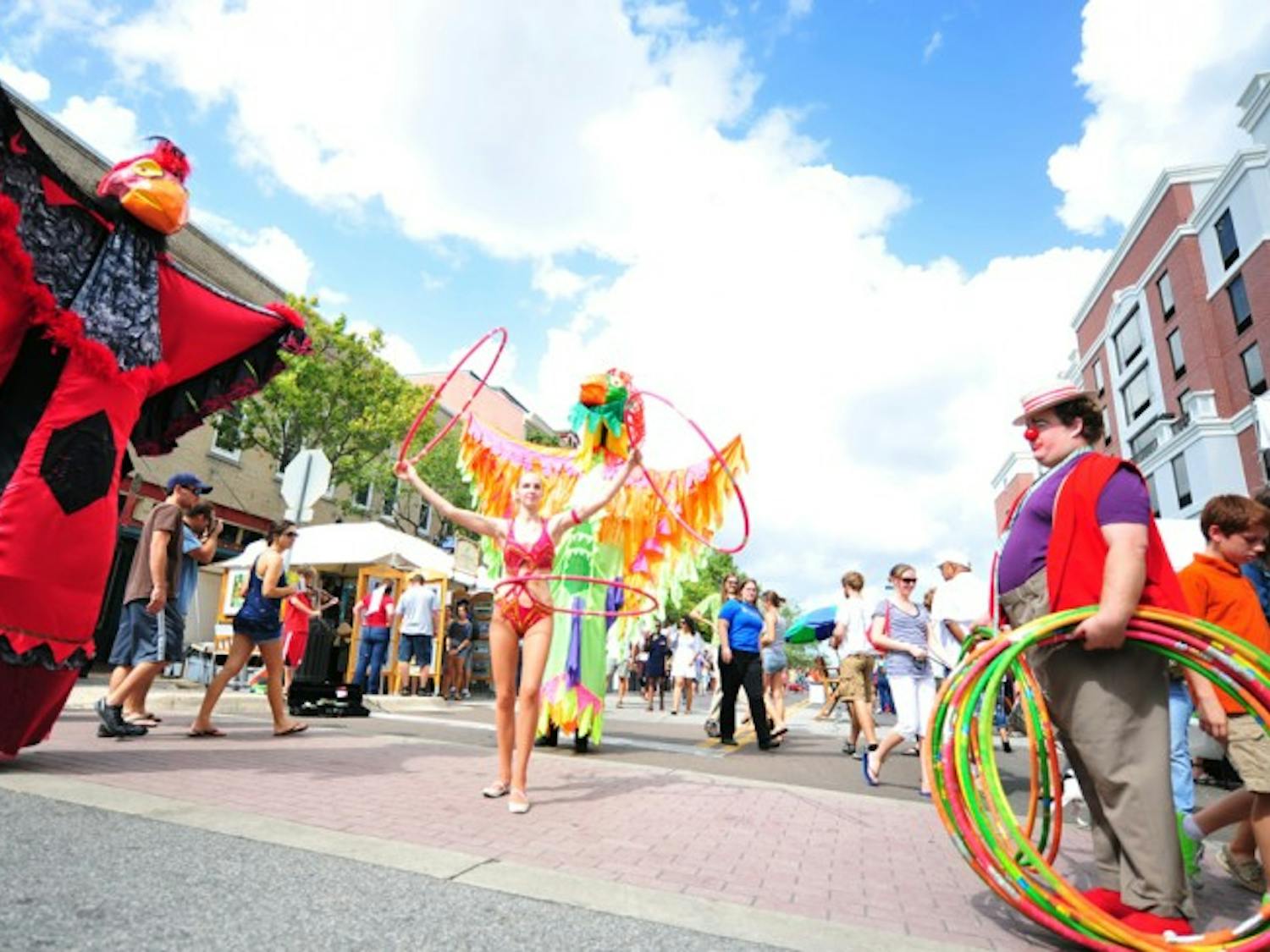 Performers Bethany Chase, in the parrot suit, Elise Duran, 22, and Clay Cox entertain in the streets of downtown Gainesville during the 2012 Downtown Festival and Art Show. They are members of the Rainbow Tiger Circus.