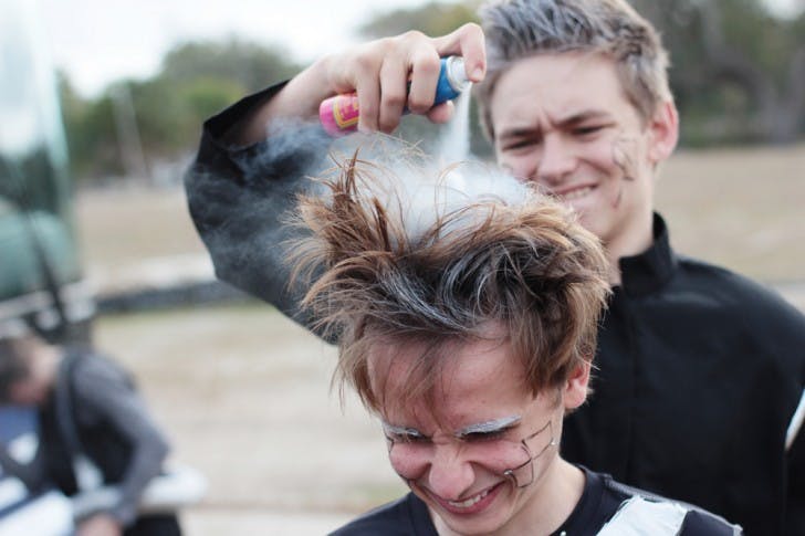 Winston Cunningham, 17, gets his hair sprayed silver by Chris Shepherd, 17, to complete his robot ensemble for a performance at the dedication ceremony for the Florida Innovation Hub at UF. Both teens are a part of the P.K. Yonge vocal ensemble.