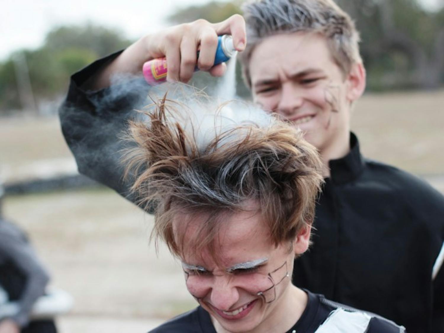 Winston Cunningham, 17, gets his hair sprayed silver by Chris Shepherd, 17, to complete his robot ensemble for a performance at the dedication ceremony for the Florida Innovation Hub at UF. Both teens are a part of the P.K. Yonge vocal ensemble.