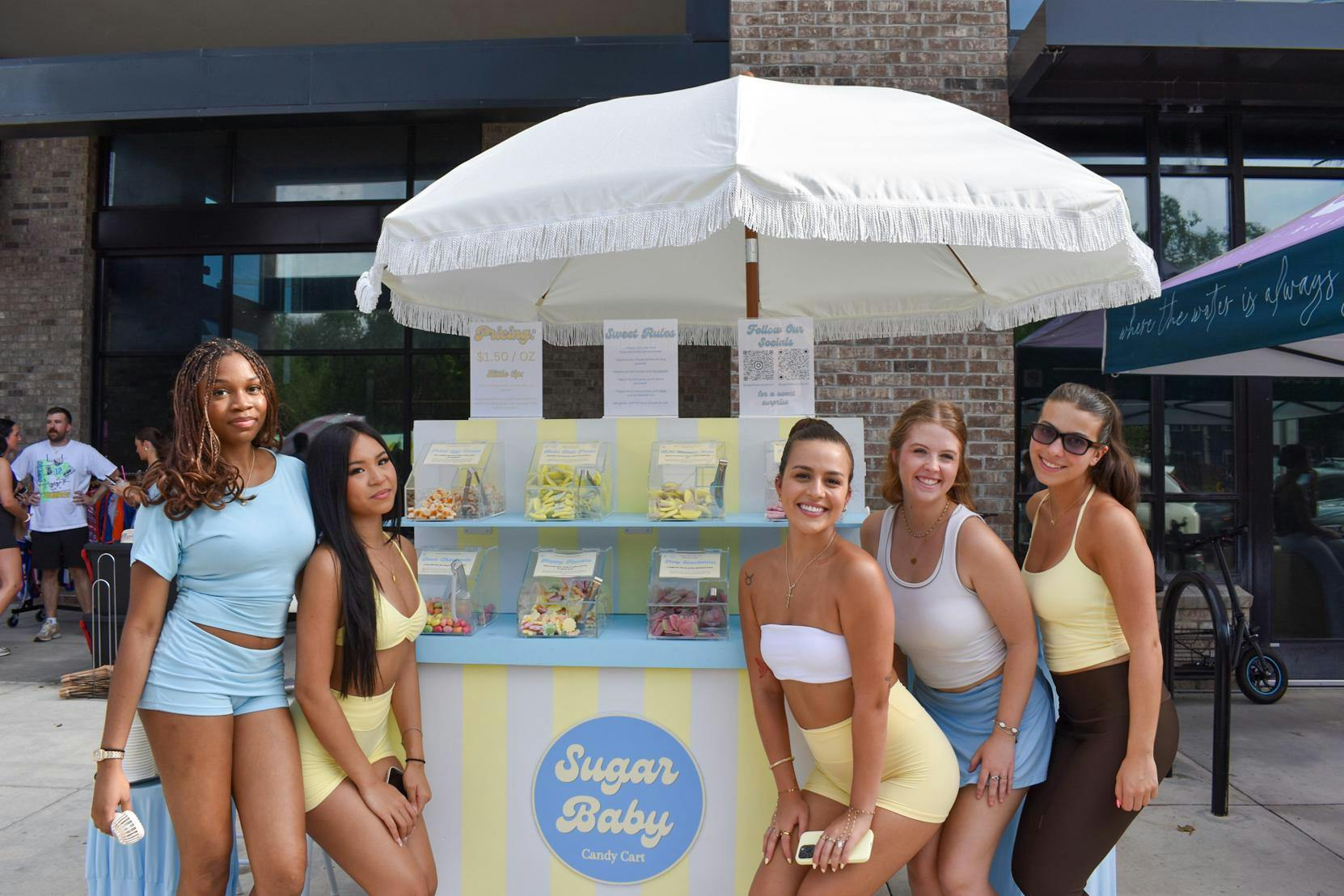 Sugar Baby staff pose in front of the Candy Cart at Peach by Pump's pop up Wednesday, Aug. 26, 2026 in Gainesville, Fla. 