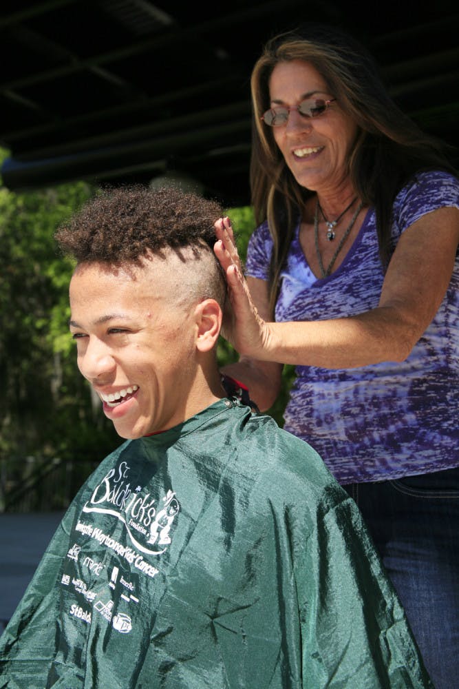 Stylist Marguerite Toigo shaves the head of 18-year-old environmental science freshman Alec Cronin at the St. Baldrick's Festival on Friday. Cronin volunteered to have his head shaved at the event to help find a cure for childhood cancer. They raised about $11,000.