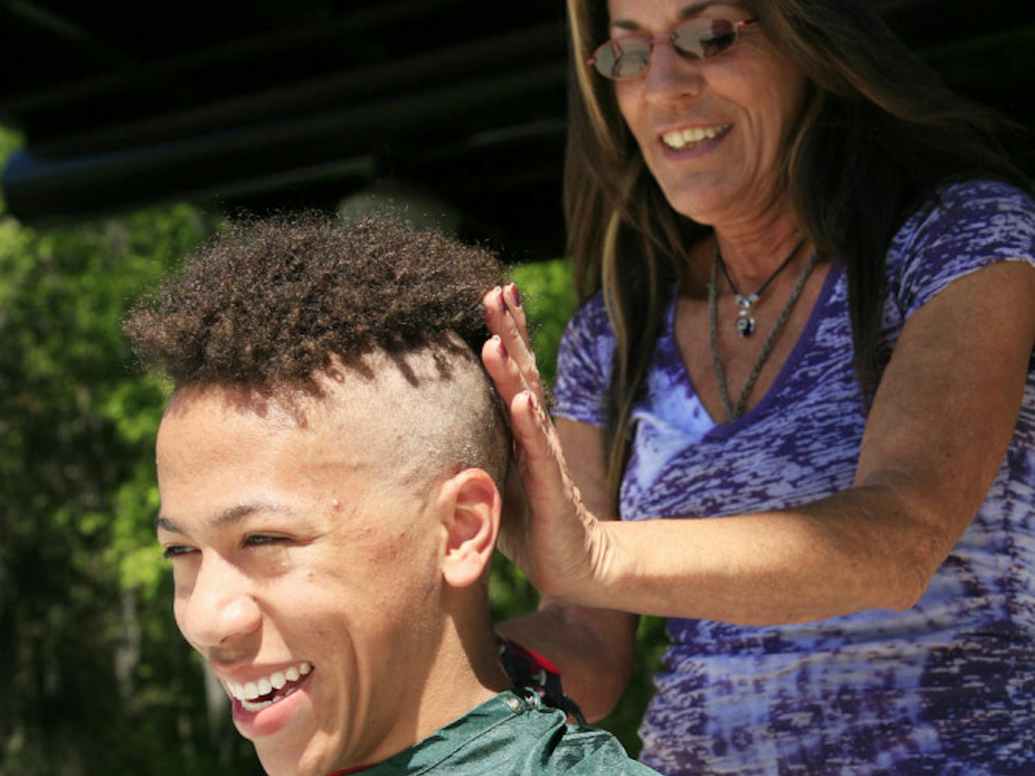 Stylist Marguerite Toigo shaves the head of 18-year-old environmental science freshman Alec Cronin at the St. Baldrick's Festival on Friday. Cronin volunteered to have his head shaved at the event to help find a cure for childhood cancer. They raised about $11,000.
