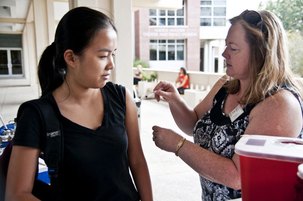 <p>Biology major Lily Pham gets a free flu shot from Kelly Mitchell, a RN at the UF Student Health Care Center, on the Reitz Union Colonnade last fall.</p>
