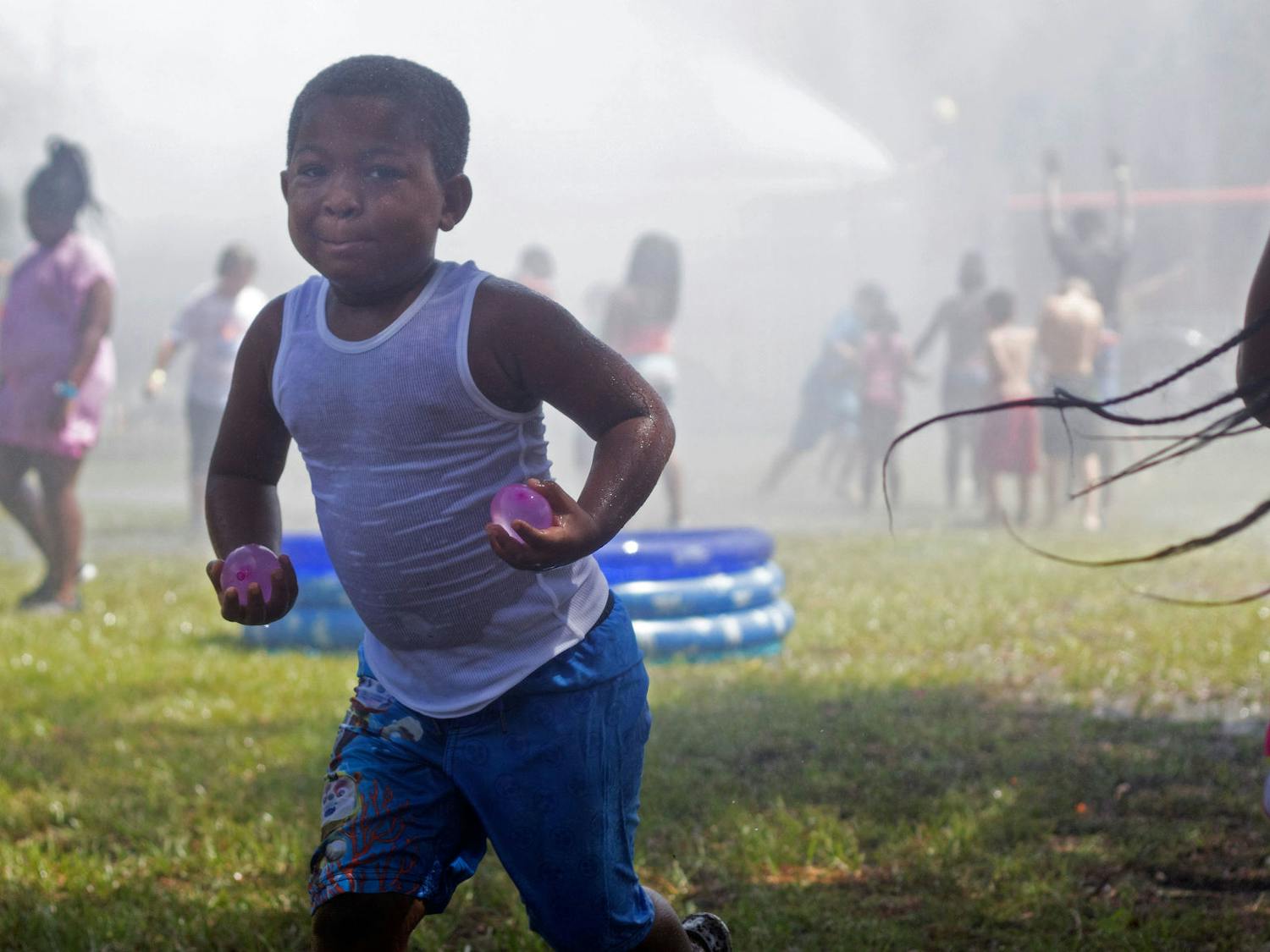 Ja’Keil Norris, 5, runs away from the firetruck hose while carrying two water balloons Saturday during Beat the Heat Water Day.
The event featured kids-versus-cops water balloon battles along with blasts of water from the deck gun of a fire truck, which was advertised as “the world’s largest sprinkler”. Firefighters atop the firetruck would spray water over the children about every ten minutes.