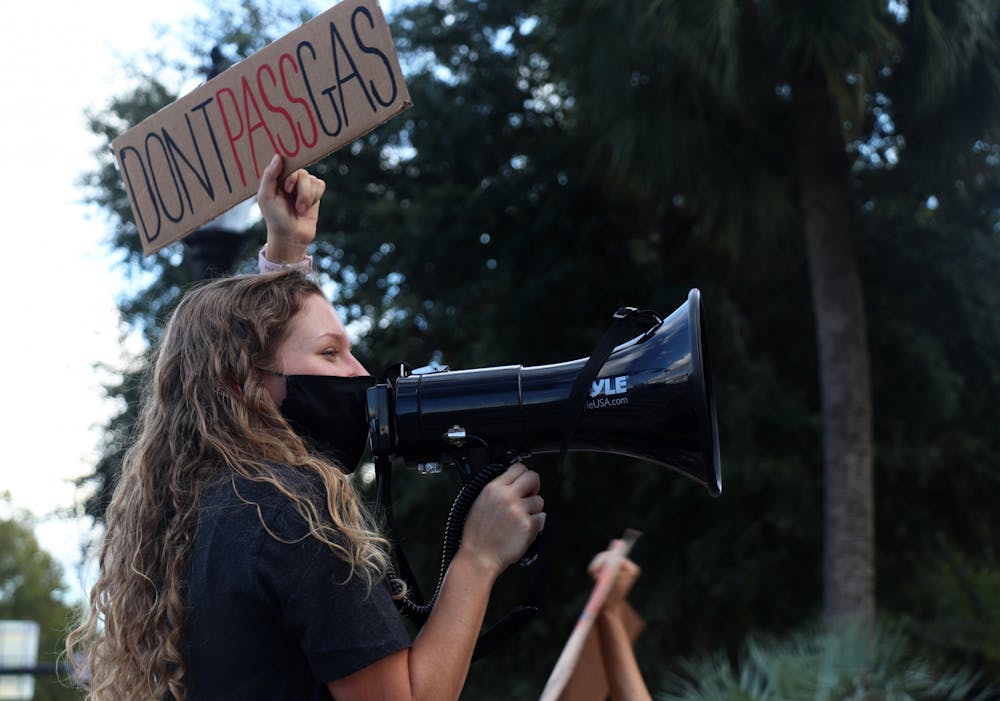 Makenzie Griffin, 22, UF zoology senior, holds a “Don’t Pass Gas” sign in protest of UF’s power plant construction during a rally at the corner of University Avenue and 13th Street on Friday, Sept. 24, 2021.  Griffin is an organizer with the Sunrise Movement, which planned the rally.