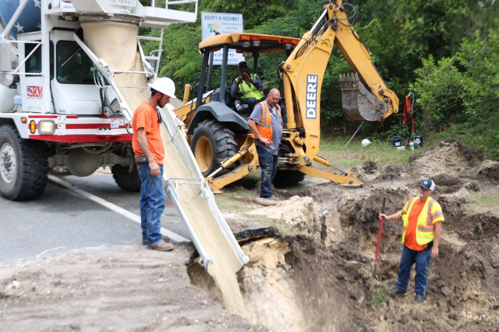 Construction workers from Newberry utilities pour concrete to fill a 20-foot deep sinkhole that opened on West Newberry Road on Wednesday morning.