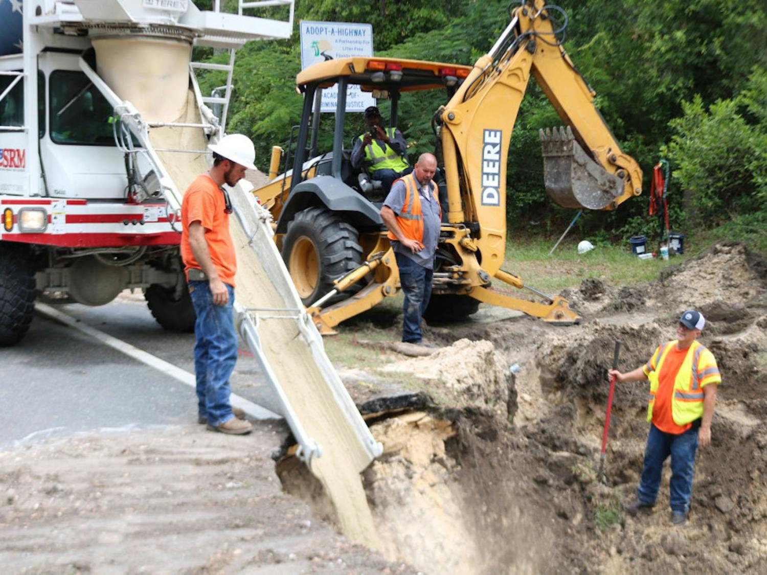 Construction workers from Newberry utilities pour concrete to fill a 20-foot deep sinkhole that opened on West Newberry Road on Wednesday morning.