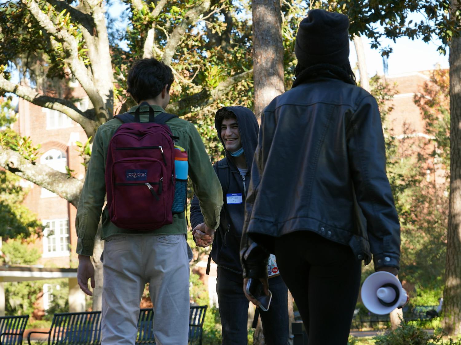 A contestant of the Luigi Mangione shakes hand with another person at the Luigi Mangione lookalike contest in the Plaza of the Americas on Thursday, Dec. 12, 2024.