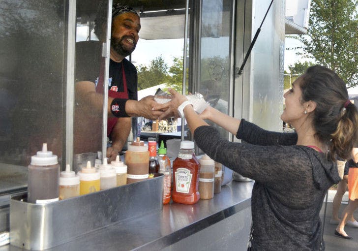 Natalia Rivera, 19, receives food from Nigel Hamm, owner and operator of Go Go Stuff Yourself/ Mobile Kitchen and Catering, at the food truck rally at Innovation Square on Friday.