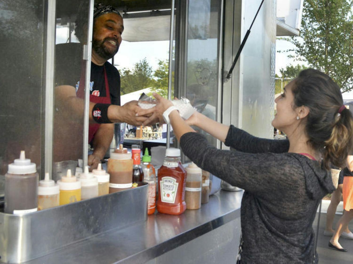Natalia Rivera, 19, receives food from Nigel Hamm, owner and operator of Go Go Stuff Yourself/ Mobile Kitchen and Catering, at the food truck rally at Innovation Square on Friday.