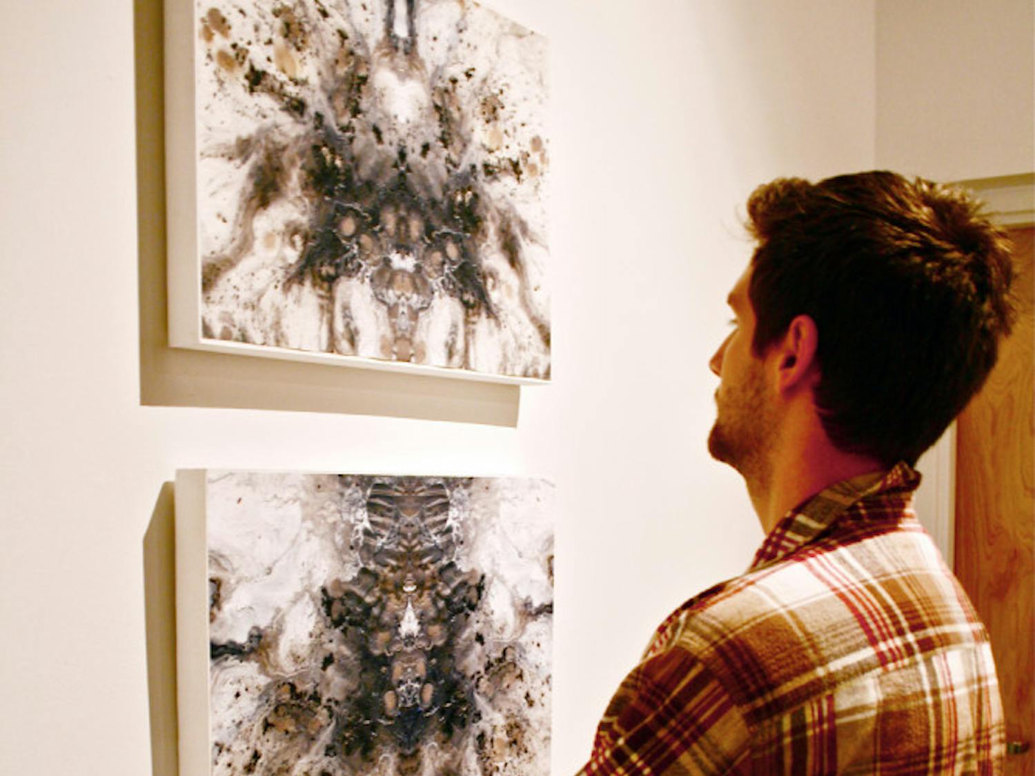 Drawing senior Domenic Henderson,21, admires the work of fellow artist Alexa Udermann, a drawing senior, at the WARPhaus gallery. The artists’  work will be on display through Feb. 6.