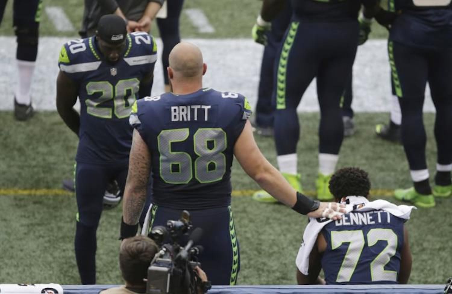 Seahawks center Justin Britt and cornerback Jeremy Lane stand near defensive end Michael Bennett as Bennett sits on the bench during the national anthem Friday, Aug. 18, 2017, in Seattle. (Scott Eklund / AP)