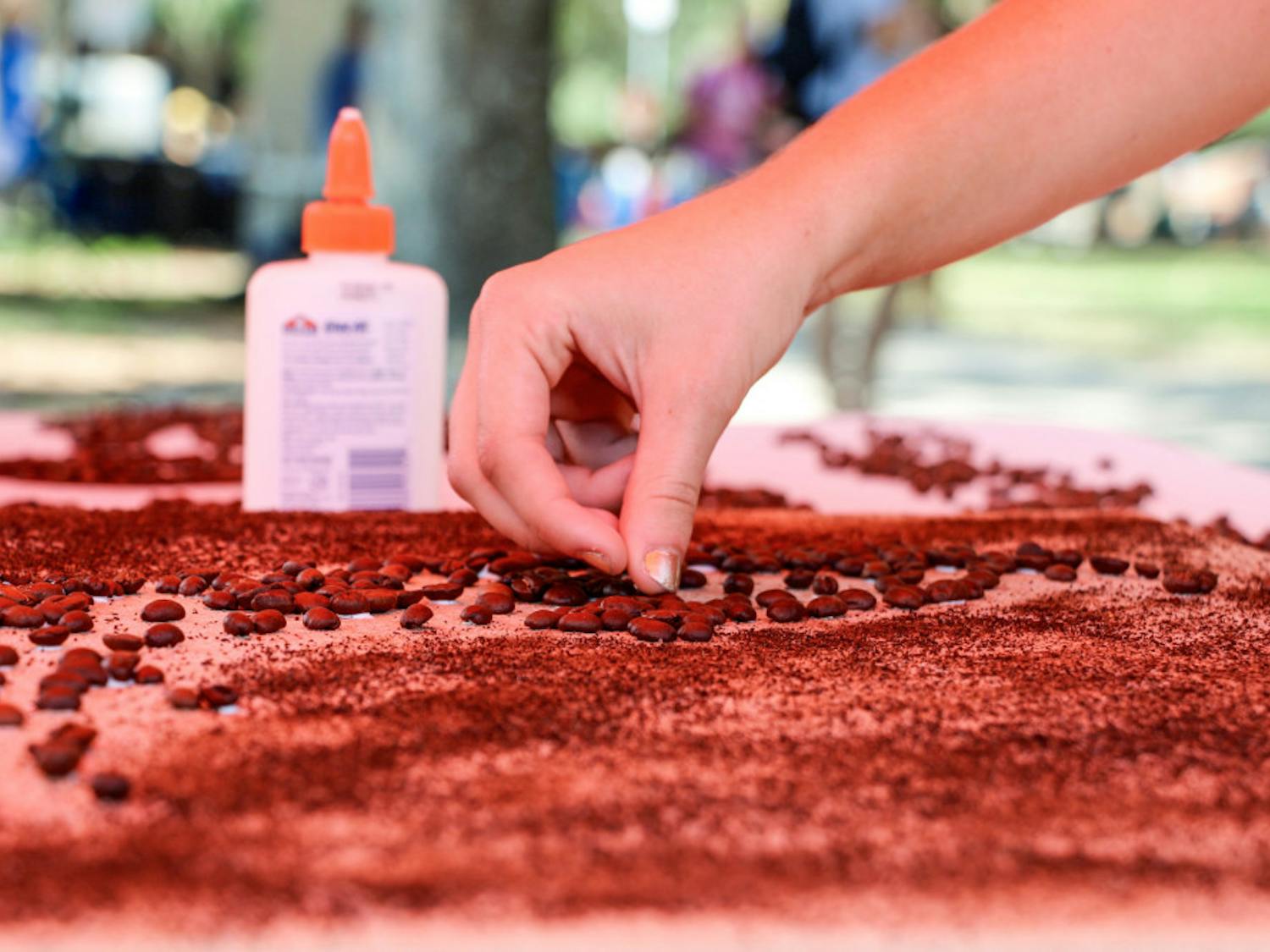 Carley Carbary, a 19-year-old UF religion freshman, places a bean in UF Social Street Team’s community art project (the state of Florida made up of coffee beans) on the Plaza of the Americas on Thursday in honor of National Coffee Day. Limited-edition buttons were given to those who contributed a bean to the project.