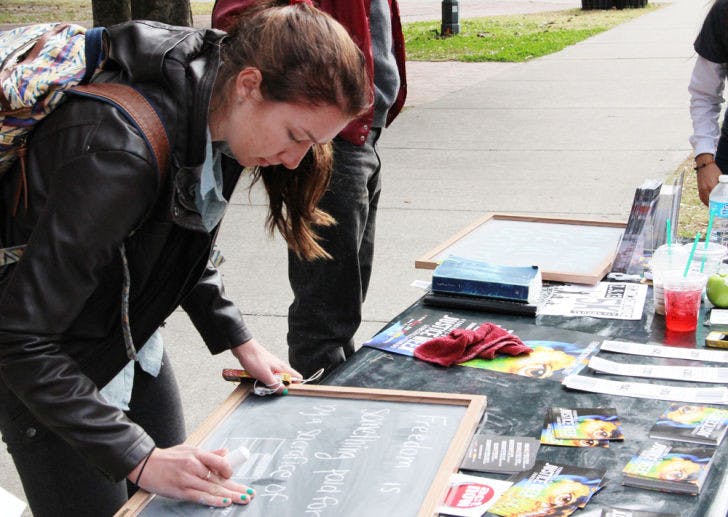Jessica Forbes, 19, a UF applied physiology and kinesiology freshman, writes on a board at a demonstration fighting against human trafficking during Justice Week on Monday on Plaza of the Americas.