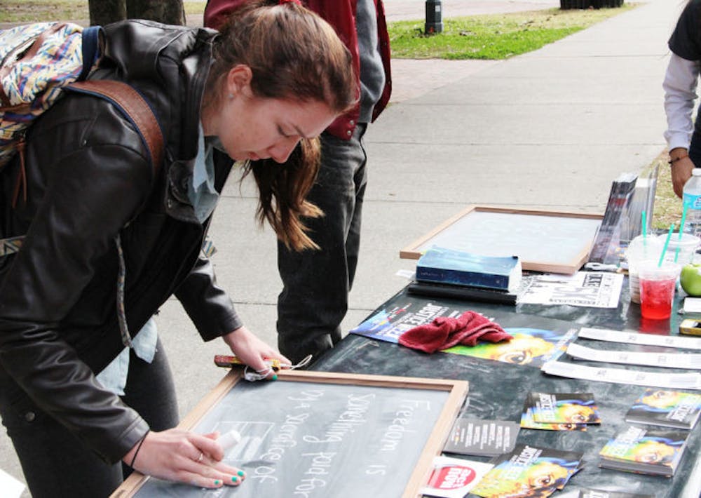 <p>Jessica Forbes, 19, a UF applied physiology and kinesiology freshman, writes on a board at a demonstration fighting against human trafficking during Justice Week on Monday on Plaza of the Americas.</p>